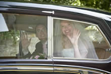 Bride and groom waving from car