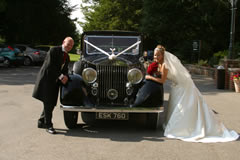 Bride and groom leaning on car